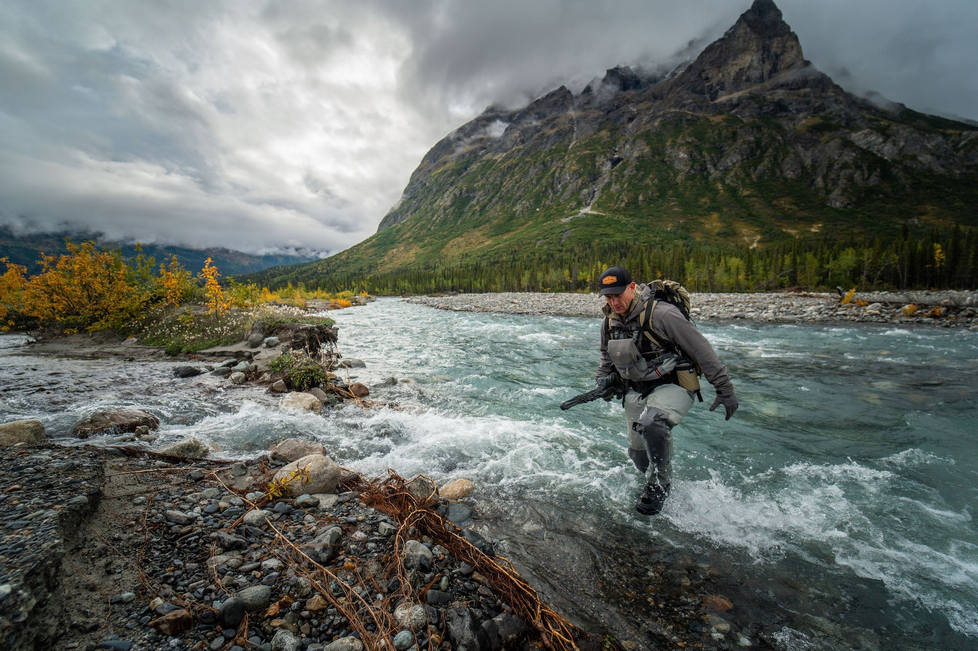 Adventurer Crossing a River in the Alaska Wilderness
