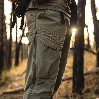 A close-up image of a backpacker wearing the Stone Glacier De Havilland LITE Pants in tarmac while standing in a wooded area.