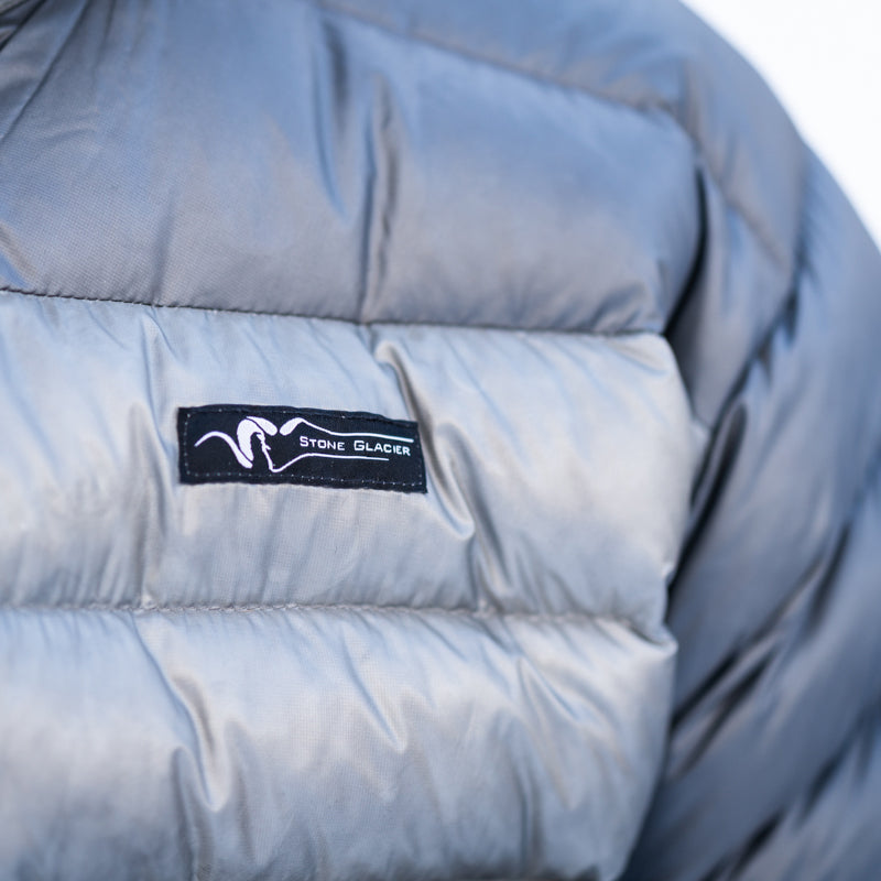 A close-up image of the product labeling found on the Stone Glacier Grumman Goose Down Jacket in granite grey.