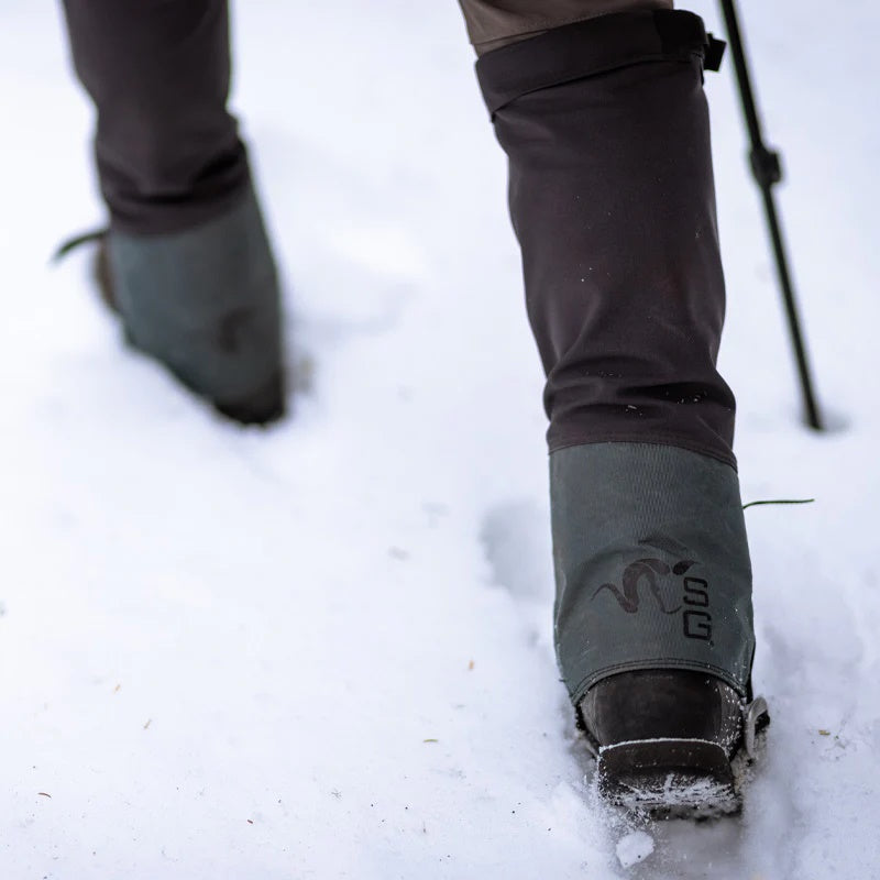 A close-up image of a backcountry hunter walking through the snow while wearing the Stone Glacier SQ2 Alpine Gaiters.